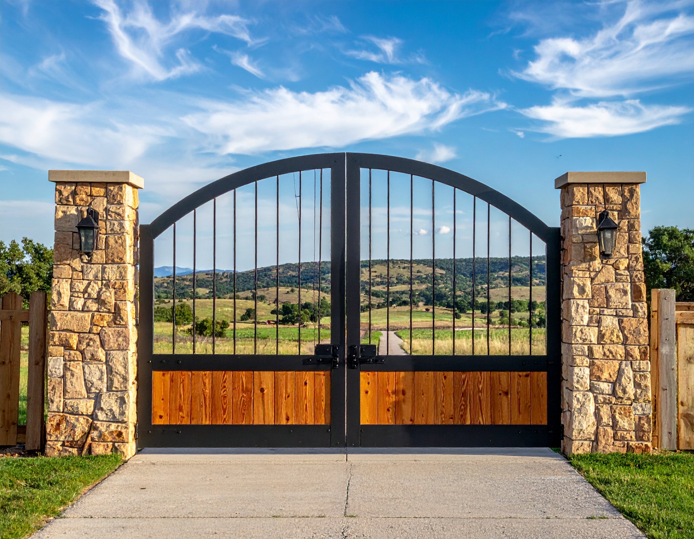 Black metal gate with stone pillars.-deck builder-San Antonio, Texas